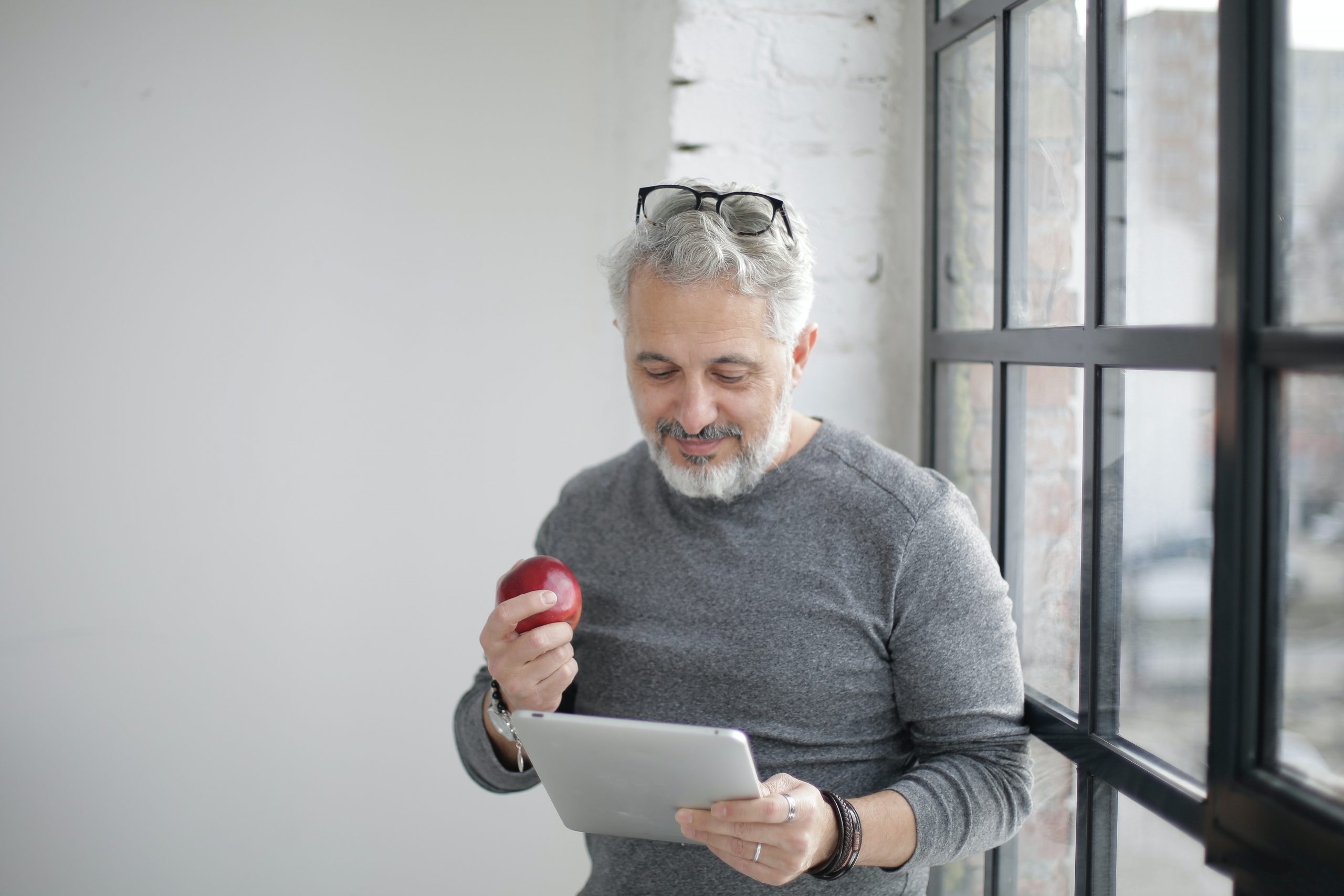 Homme étudiant avec une tablette et croquant une pomme